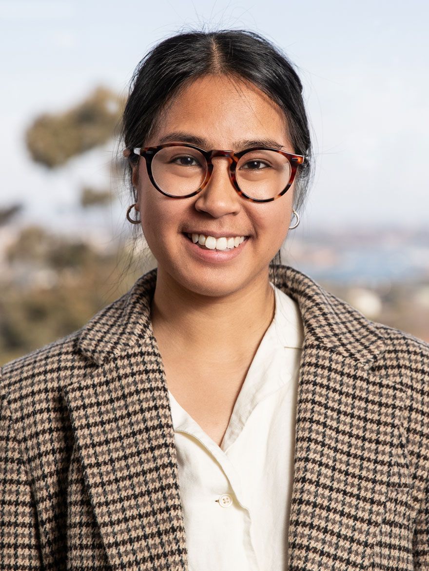 A woman with tortoiseshell glasses and a plaid brown coat. 